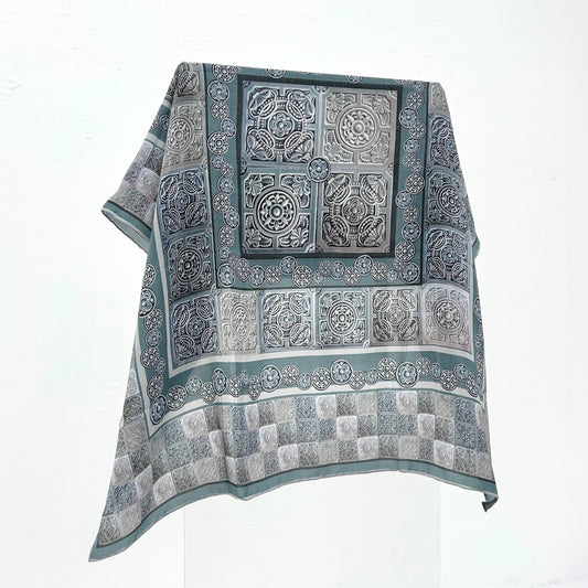 A grey patterned scarf on a white background. 