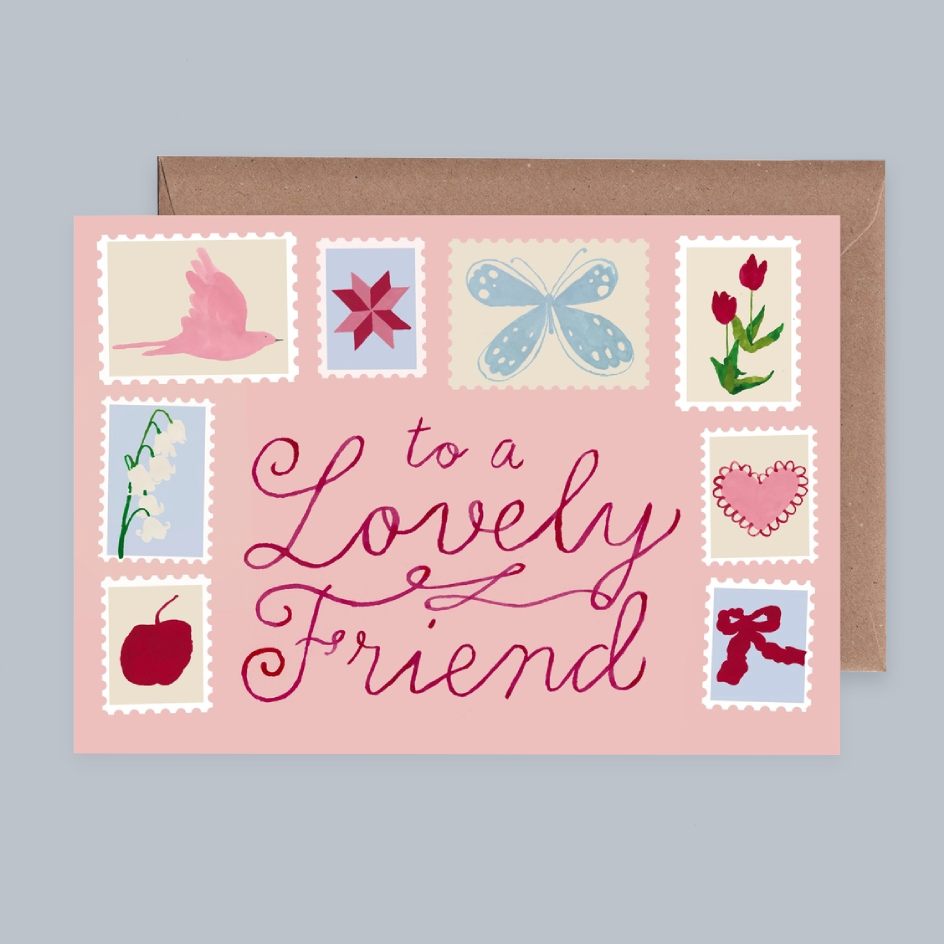 A pink greeting card with decorative illustrated stamps and the phrase “to a Lovely Friend” in cursive, shown with a brown envelope on a light gray background.