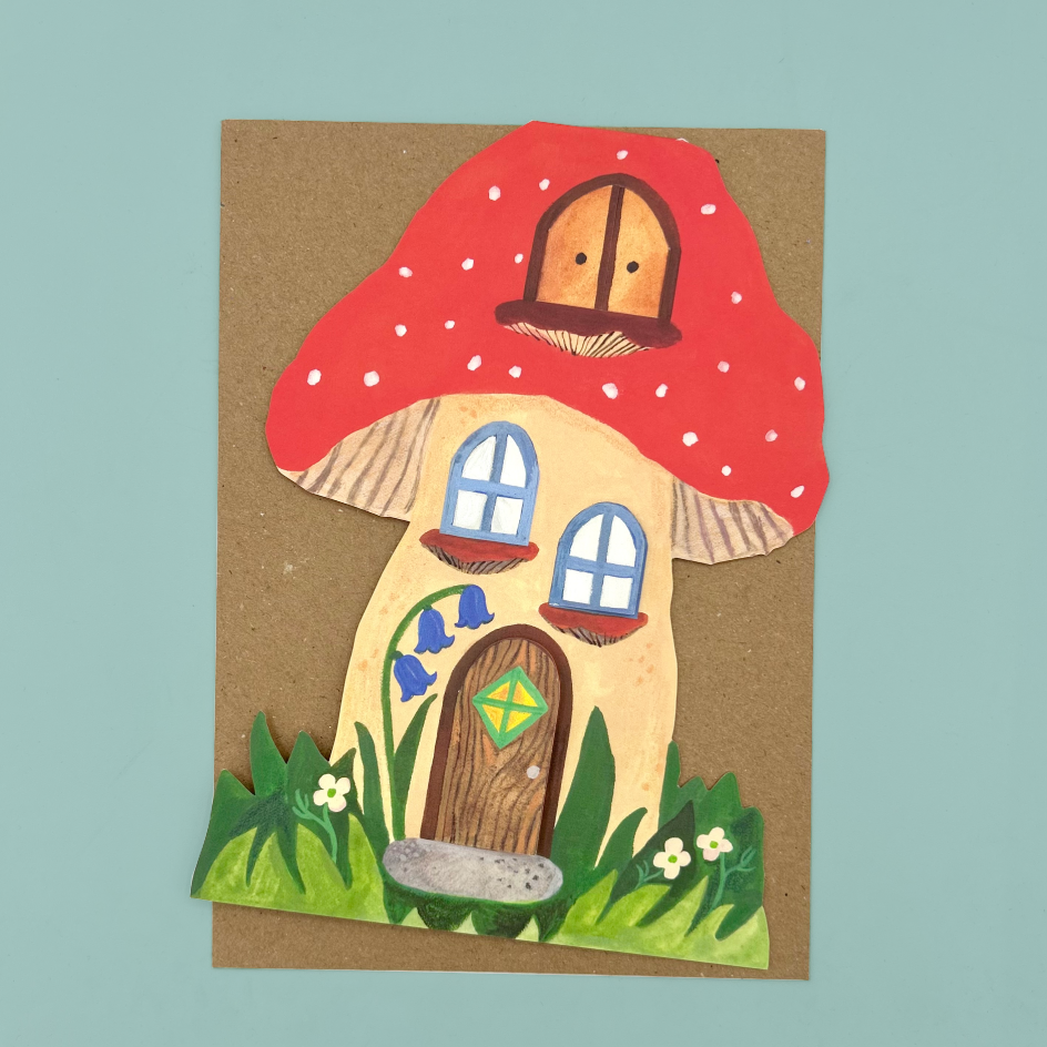 A greetings cards shaped like a mushroom house with a red spotted cap, beige body, blue windows, green grass, and small flowers, displayed on a light blue background.