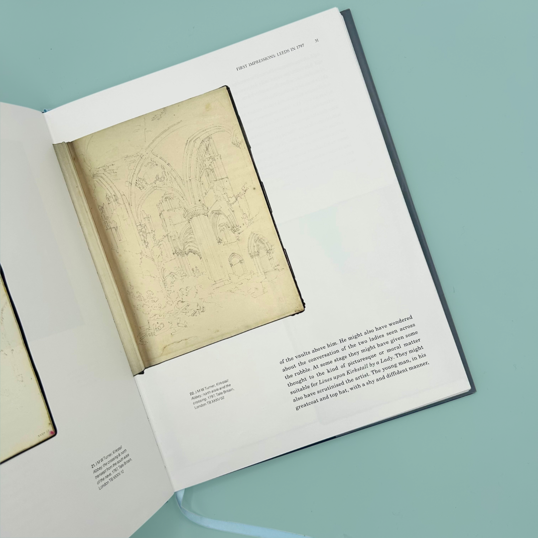 Open book with sketches of Kirkstall Abbey and text on a light blue background
