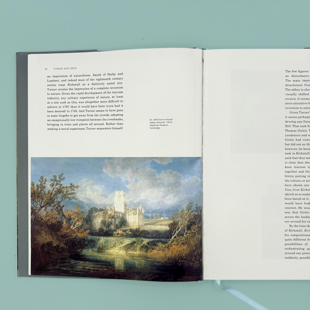 Open book with a landscape painting of Kirkstall Abbey on a light blue background