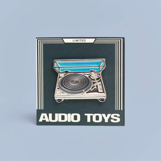 Pin of a turntable with 'Audio Toys' branding on a dark background