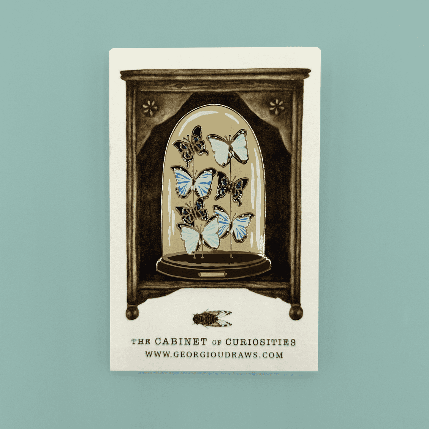 Butterfly dome pin badge on a decorative backing card.