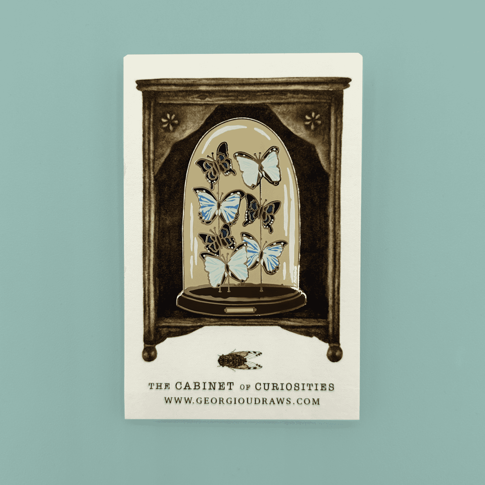 Butterfly dome pin badge on a decorative backing card.