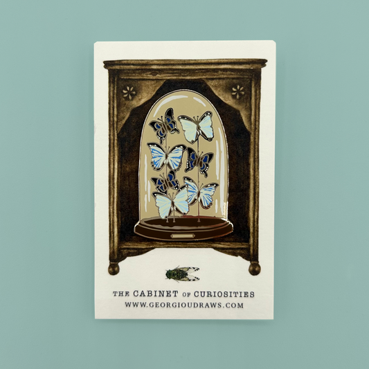 Butterfly dome pin badge on a decorative backing card.
