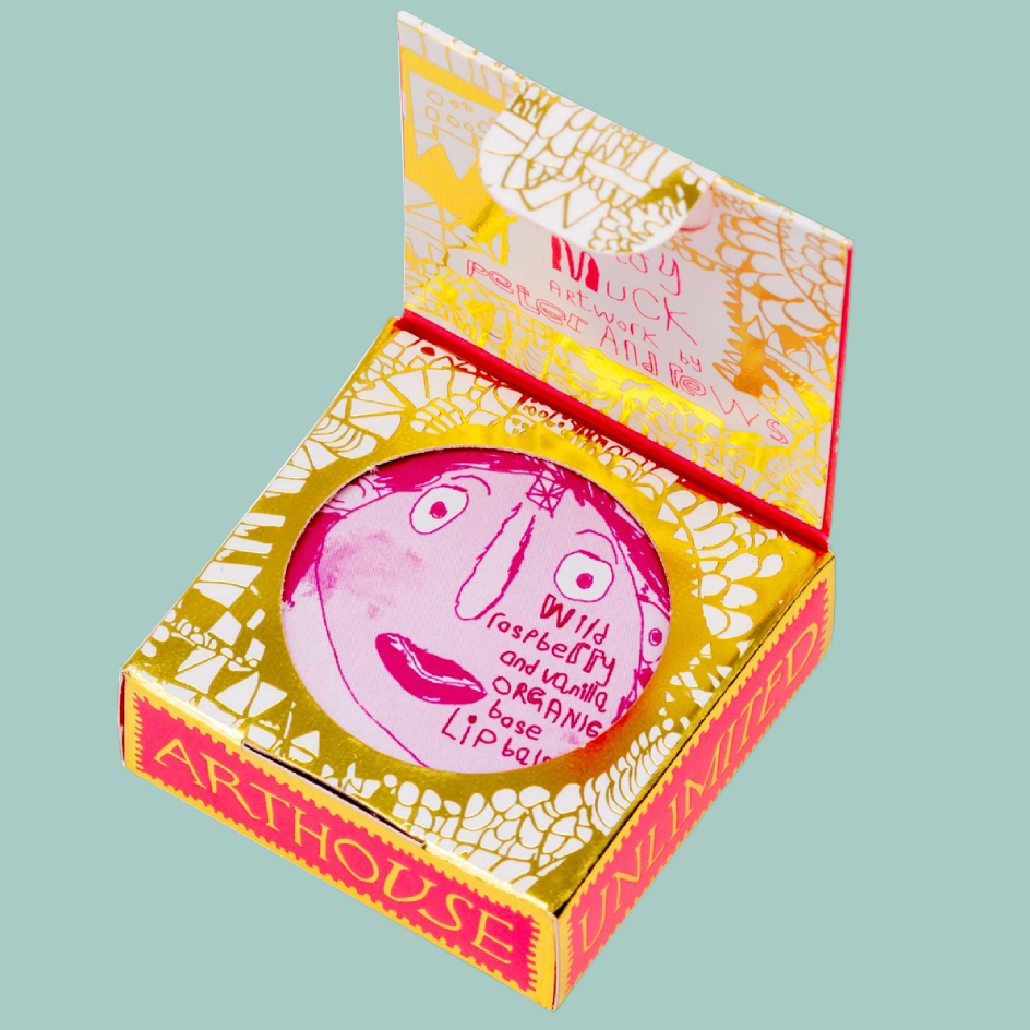 An open Arthouse Unlimited lip blam box, featuring a pink and white illustrated design with gold foil patterns.