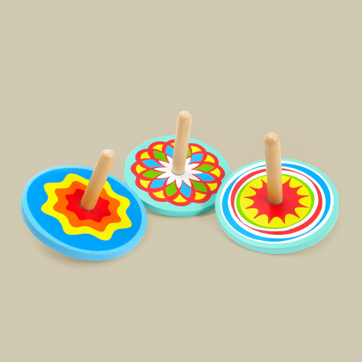 3 mutlicolour spinning tops on a biege background.