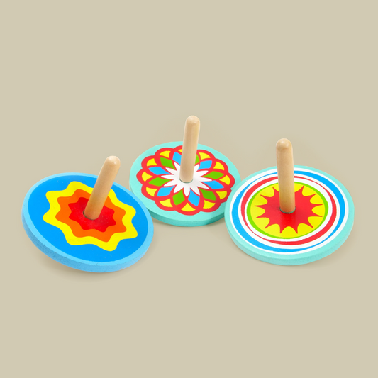 3 mutlicolour spinning tops on a biege background.