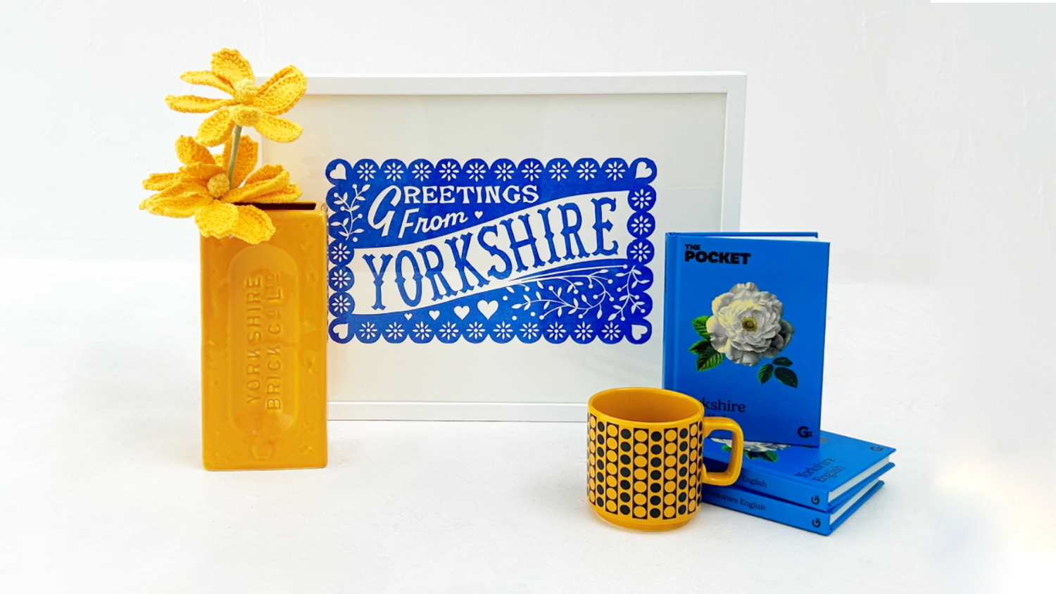 Decorative items including a mug, books, and a framed print with 'Greetings from Yorkshire' text on a white background.