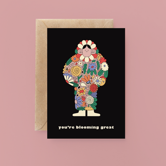Greeting card with floral design and 'you're blooming great' text on a black background, with a brown envelope.